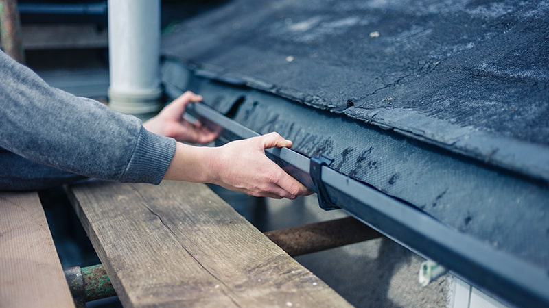 Man repairing his rain gutters on his house, repair gutters